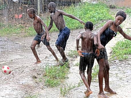 Children playing football in the rain.
